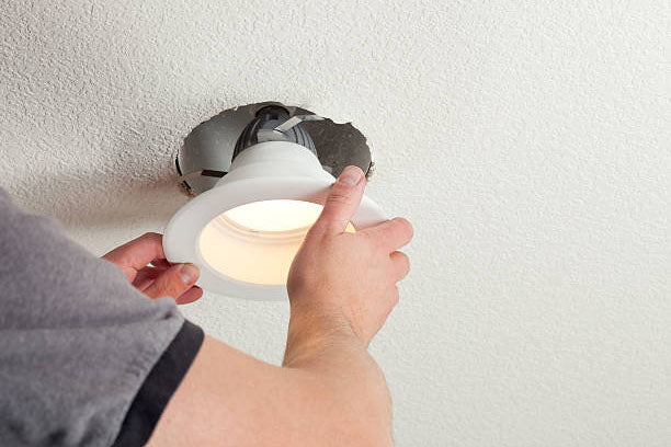 Electrician installing a down light into a ceiling
